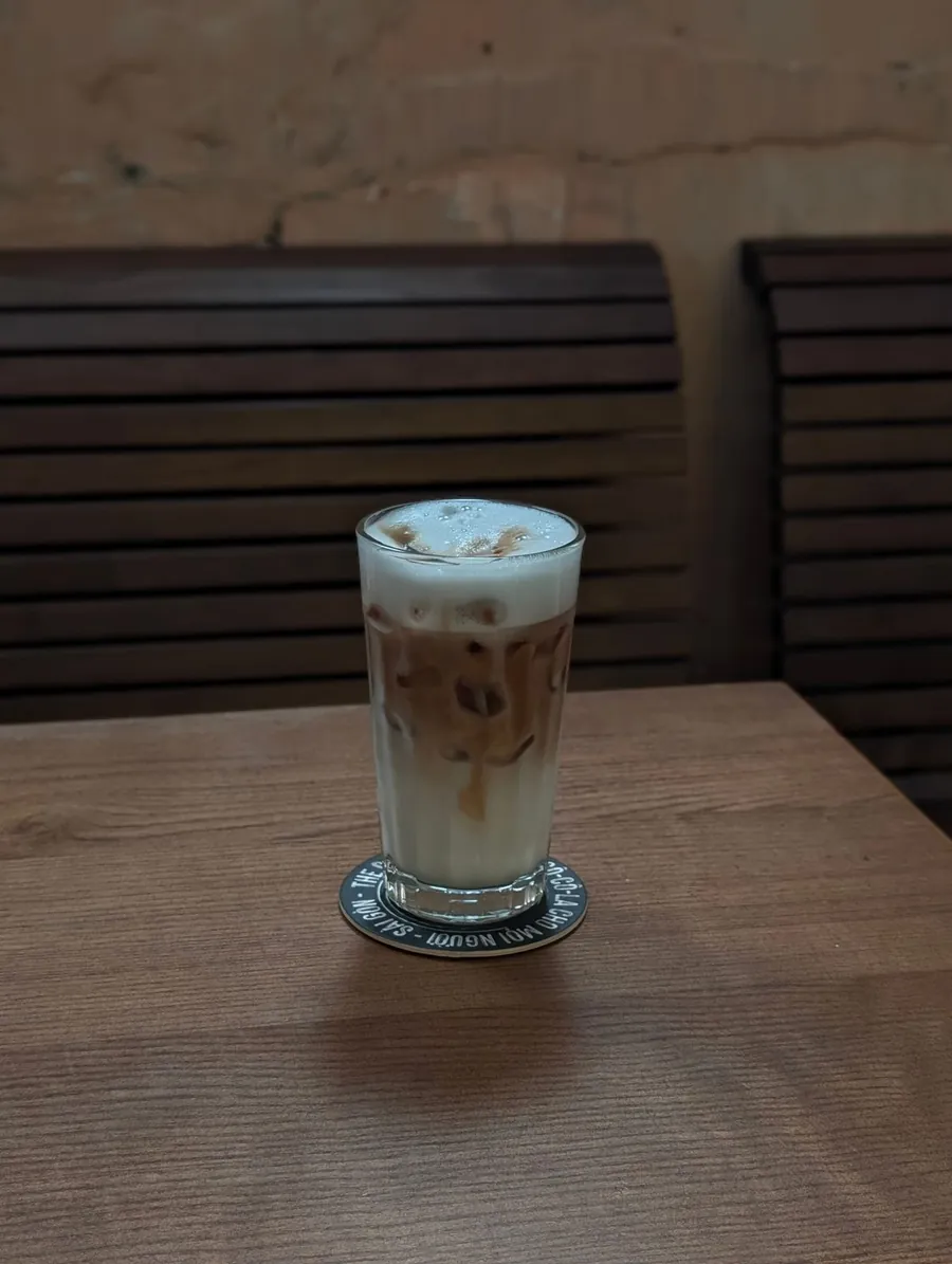 Signature Latte served iced in a tall glass on a wooden table